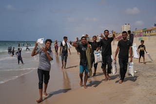 Palestinians collect aid that landed in the Mediterranean Sea after being airdropped over central Gaza, at the shore of Zawaida, Gaza Strip